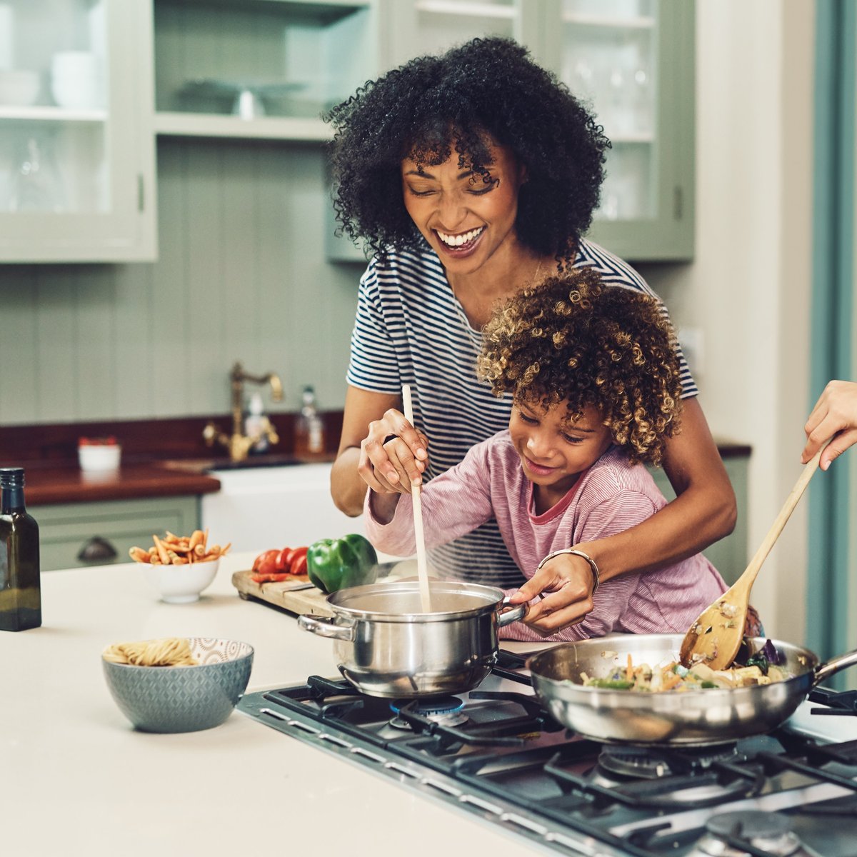 A young boy cooking alongside his mother at home, building everyday skills