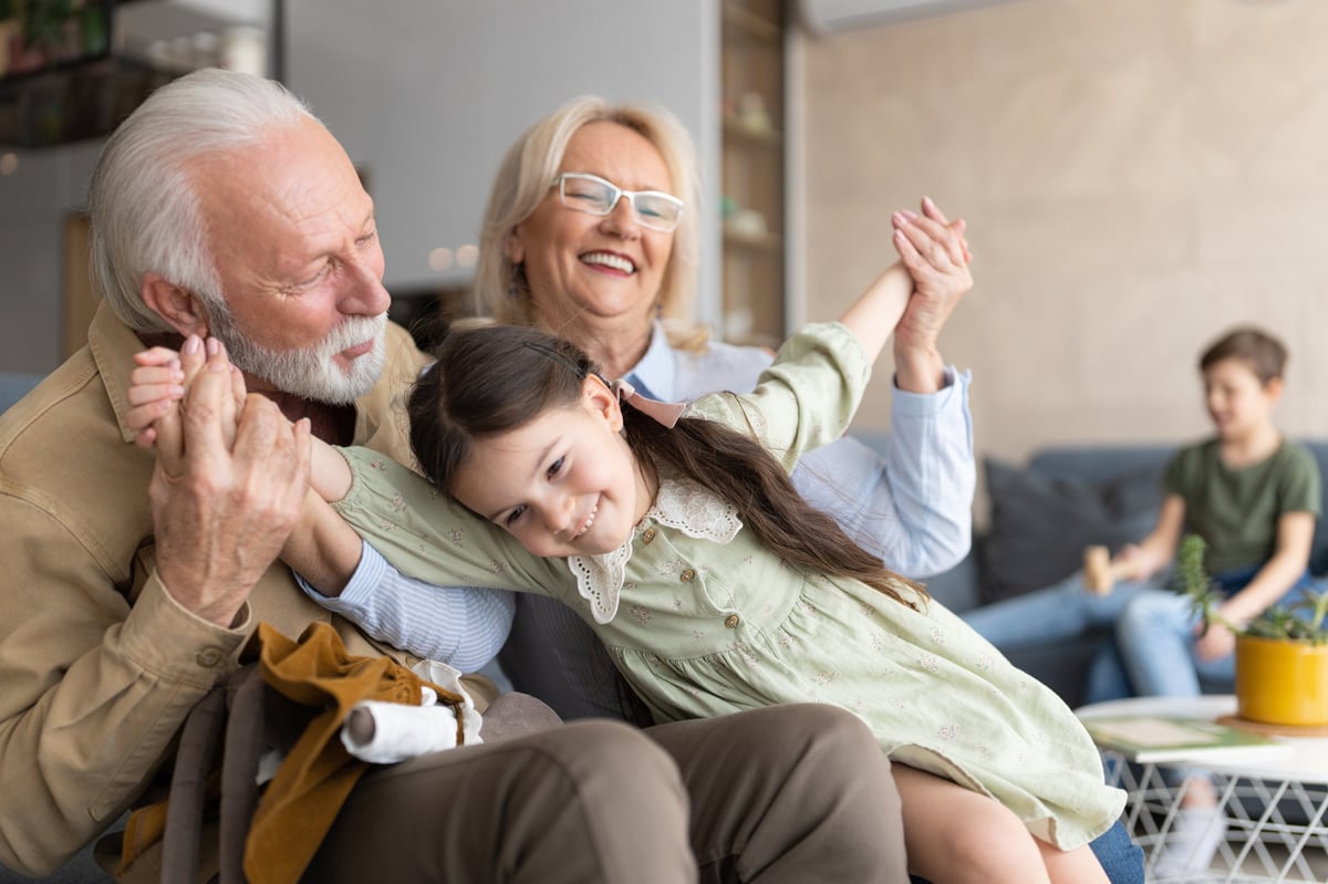 Grandparents spending quality time with their granddaughter on the sofa, smiling and playing