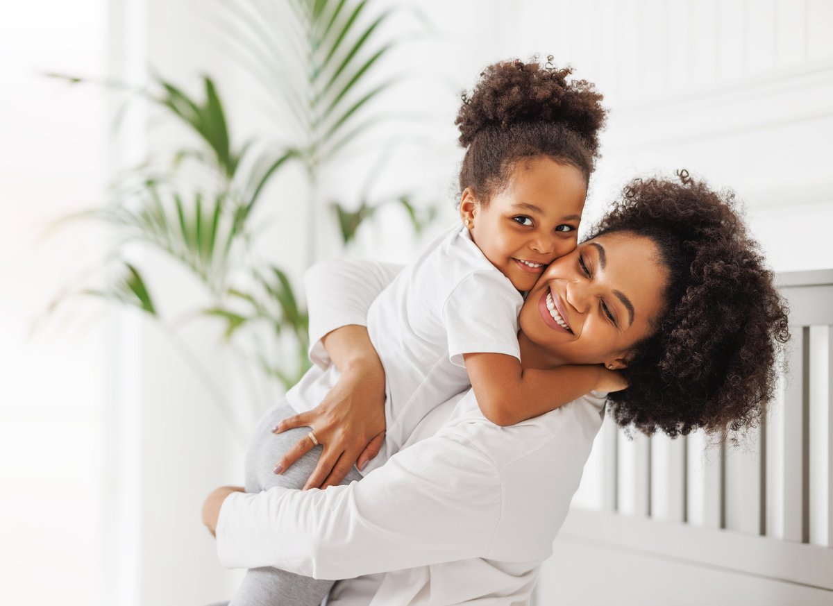 A Black mother and her daughter laughing together at home, a warm everyday moment
